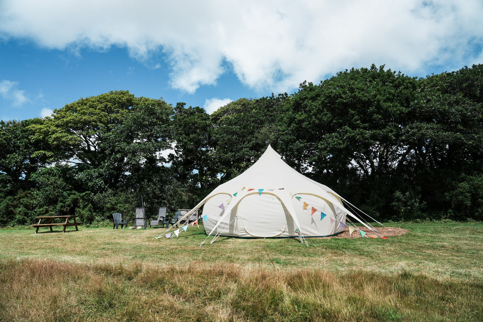 Outback Tents. Picture of a Lotus Belle Tent pitched in a field. A luxury, canvas bell tent, but with lots of standing room. Perfect for glamping, events & parties